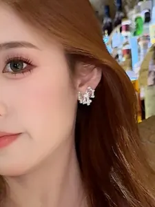 Detalle de elegante pendiente de mariposa plateada con perlas usado por una modelo asiática