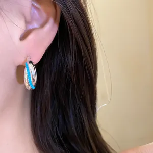 Silver chunky hoop earring with small turquoise bead detail shown on a model's ear