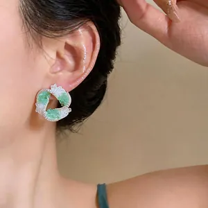 Elegant detail of geometric earrings featuring green and white glass with zircon pave