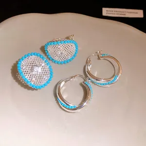 Detailed view of silver hollow lattice stud earrings with zircon and blue beads