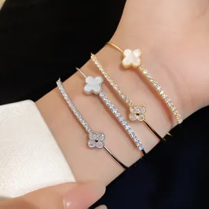 Close-up of elegant gold and silver four-leaf clover bracelets with zircon accents.