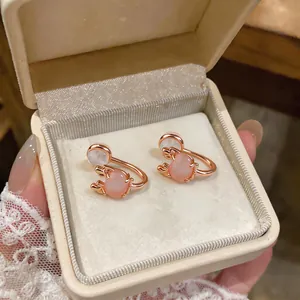 Close-up view of pink cat eye stone oval clip-on earrings in a cream velvet jewelry box