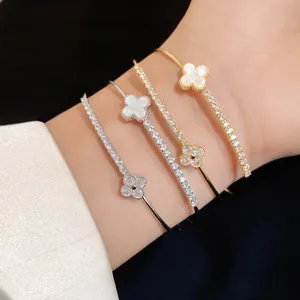Close-up detail of four-leaf clover bracelets with sparkling zircons and white shell inlay.