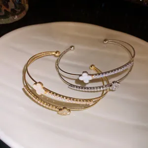 Macro detail of double-layer zirconia four-leaf clover open cuff bangle with gold finish