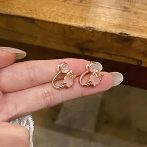 Close-up detail of pink cat's eye stone clip-on earrings in rose gold finish