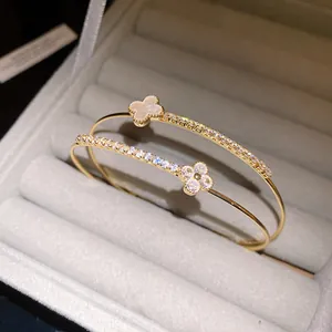 Macro detail of gold-plated bangle with zircon-studded and mother-of-pearl clover motifs