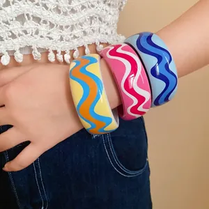 Joncs colorés en résine à motifs ondulés portés au poignet du mannequin