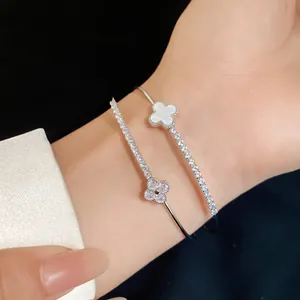 Detailed view of a double-layered open bangle with sparkling clover charms on a wrist