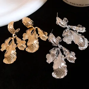 Close-up detail of vintage gold and silver metal leaf drop earrings on dark background