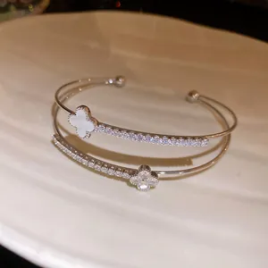 Detail of an elegant double-layer silver zircon clover bracelet with white floral shell inlay