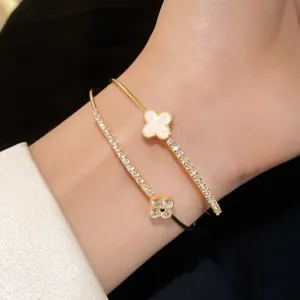 Close-up of a double-layer gold bangle featuring zirconia and clover motifs on a wrist.