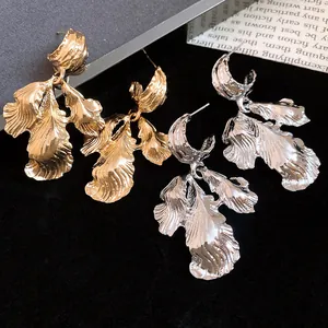 Detailed shot of vintage gold and silver leaf earrings with textured metallic finish.