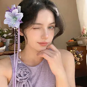 Elegant purple fabric flower hair clip with pearl tassels and ribbon shown on model