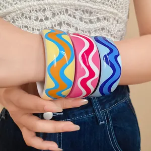 Gros plan de trois bracelets en résine ondulés colorés portés au poignet, style rétro.