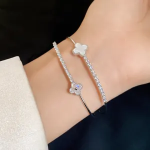 Macro detail of a silver double-layer open bangle with zircons and a shell clover motif