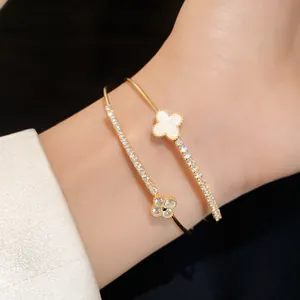 Close-up of a double-layer gold-tone bracelet with white shell and zircon clover charms.