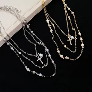 Elegante collana multistrato con perle e ciondoli a croce in cristallo scintillante.