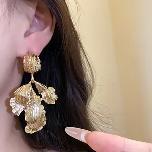 Detailed close-up of vintage gold-toned leaf pendant earring on model for an elegant look