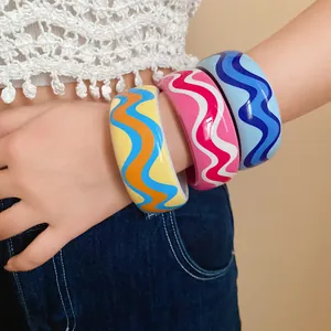 Vue détaillée de trois joncs en résine aux motifs de vagues colorées portés par le modèle