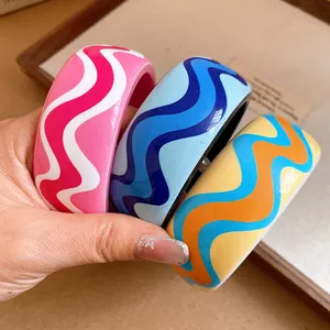 Gros plan de bracelets en résine colorée avec motif ondulé et finition émaillée.