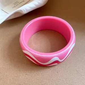 Vue détaillée d'un bracelet jonc en résine rose avec un motif de vagues et fini mat