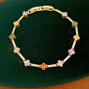 Detailed view of 14k gold plated clover bracelet with colorful zircons on green velvet cloth