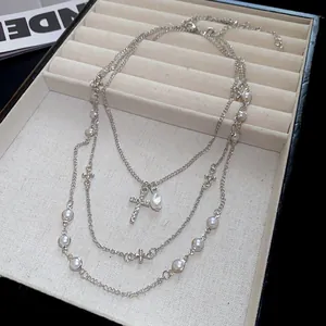 Dettaglio di un'elegante collana d'argento multistrato con perle e ciondoli a croce