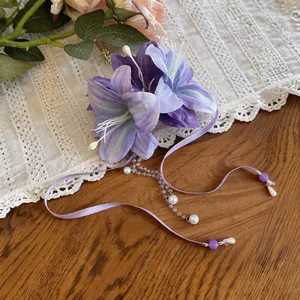 Close-up of elegant purple fabric flower hairpin with ribbon tassels and pearls for hair.
