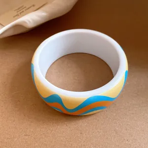 Gros plan d'un bracelet jonc rétro en résine avec des motifs de vagues bleues et orange