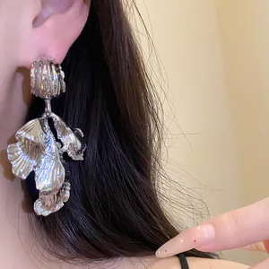 Macro shot of vintage silver metal leaf pendant earrings worn by an Asian model