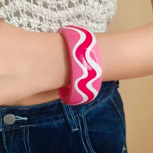 Détail d'un bracelet en résine rose avec des motifs de vagues blancs et magenta vifs