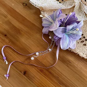 Detail view of elegant purple fabric flower hair clip with pearl tassels and ribbons