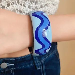 Vue détaillée d'un bracelet en résine à motif de vagues bleues sur le poignet d'un mannequin