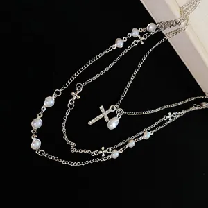 Elegante dettaglio di collana multistrato con perle bianche e croce di strass lucenti