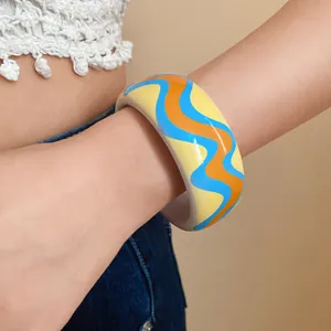 Détail en gros plan d'un bracelet en résine coloré aux motifs de vagues bleues et orange