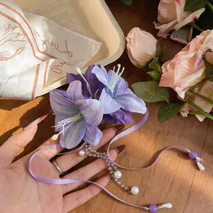 Close-up detail of a purple fabric flower hair clip with pearl tassels and ribbons
