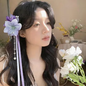Close-up detail of an elegant purple fabric flower hair clip with pearl tassels and ribbons