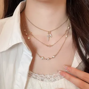 Elegante collana a strati color oro con ciondolo a croce di diamanti e piccole perle
