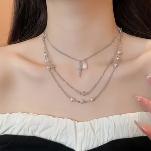 Dettaglio di una collana d'argento a più strati con eleganti perle e ciondoli a croce.