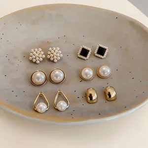 Macro view of a French style six-pair pearl and gold-tone earring set displayed on a dish