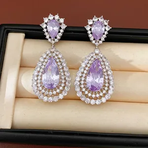 Macro detail of luxurious purple teardrop zircon earrings with layered hollowed design