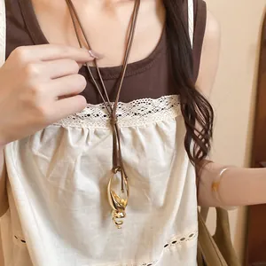 Vista dettagliata di un'elegante collana con ciondolo a conchiglia su cordoncino.