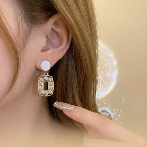Vintage gold hollow square dangle earrings with sparkling rhinestones worn on ear
