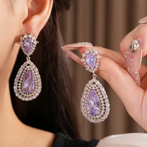 Close-up detail of luxurious purple teardrop zircon earrings with intricate hollow patterns