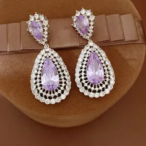 Detailed view of elegant purple zircon teardrop earrings on a brown velvet jewelry box.