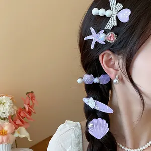 Close-up of model wearing purple starfish and shell hair clips with pearls and rhinestones.