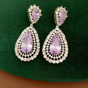 Elegant purple zircon teardrop earrings with micro-pave hollow design on green velvet