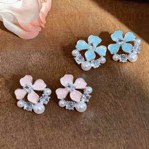 Close-up of elegant enamel flower stud earrings with pearls and zirconia