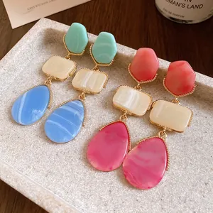 Detail shot of elegant multi-color geometric resin drop earrings on a stone tray