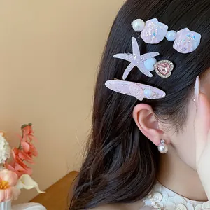Detailed view of elegant sea star and shell pearl hair clips worn on wavy brunette hair.
